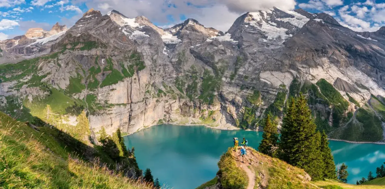 Trois randonneurs contemplent un lac turquoise spectaculaire au c&oelig;ur des Alpes. Une rando alpes inoubliable.