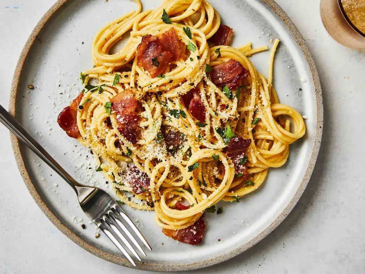 Spaghetti crémeux, parsemé de lardons croustillants et de persil frais. Une vraie recette carbonara italienne qui met l'eau à la bouche.