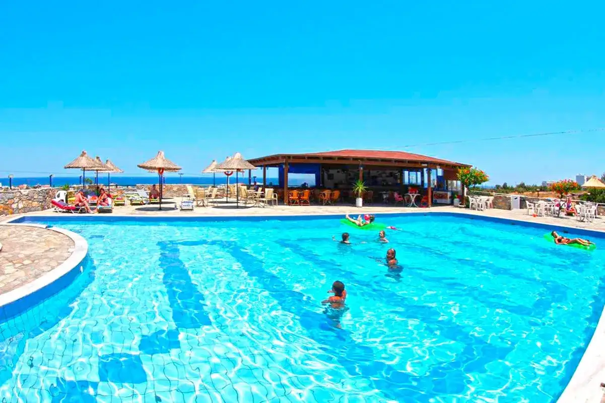 Basen z ludźmi relaksującymi się na materacach i pływającymi. W tle bar i leżaki pod parasolami. Idealne miejsce na wakacje, jak sugerują ocean heights view hotel opinie.