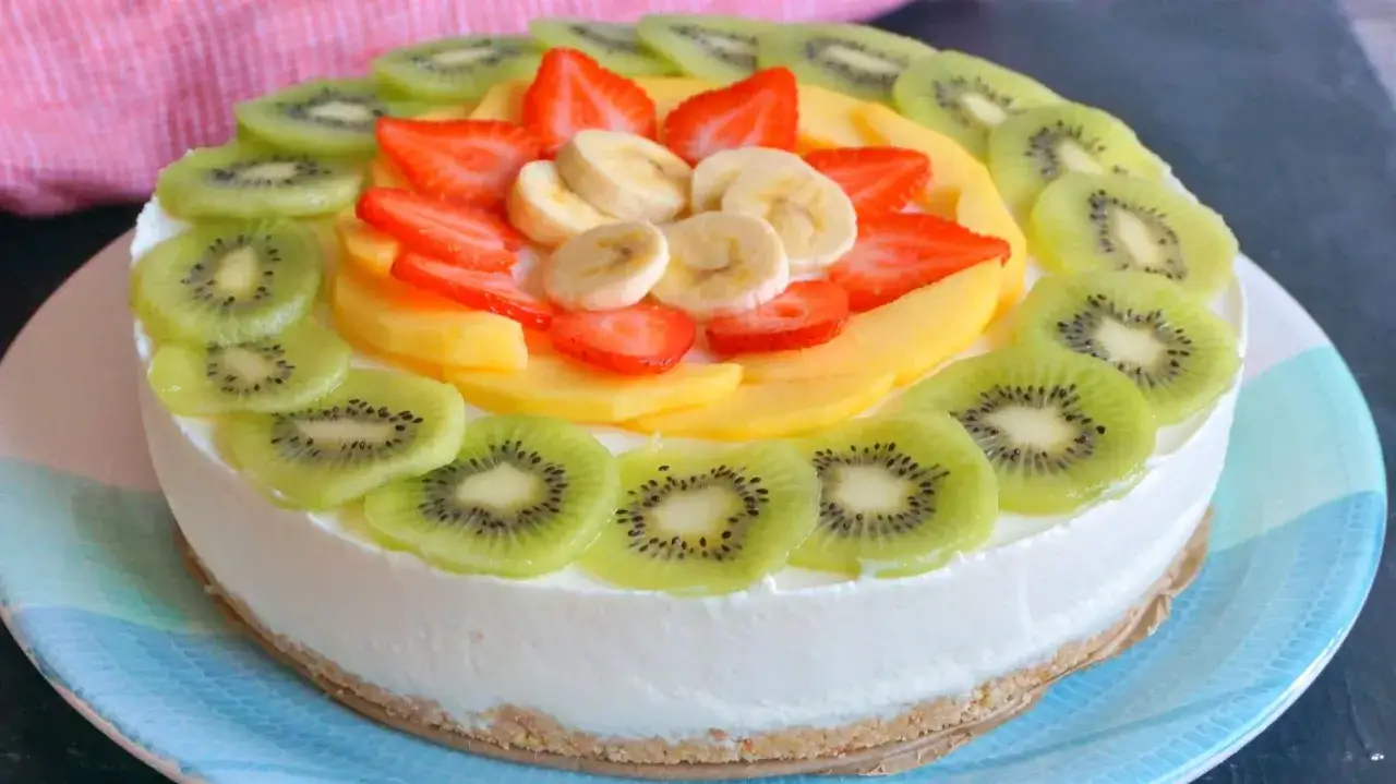 Tarta de frutas fresca y colorida, decorada con rodajas de kiwi, fresas, plátano y mango. ¡Una delicia visual y gustativa!