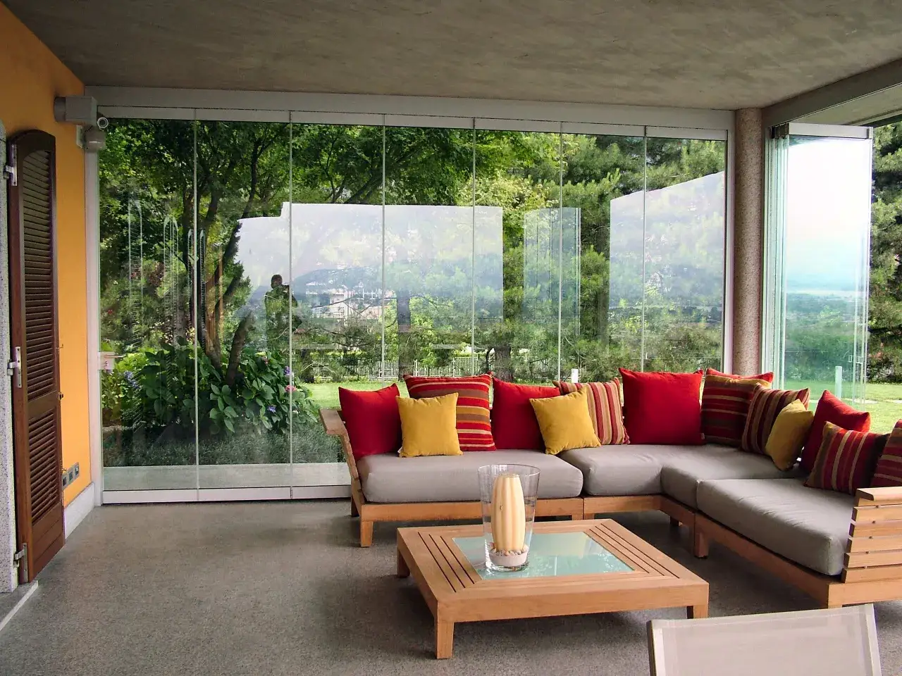 Un angolo relax con divano angolare, tavolino in legno e cuscini colorati, ideale per idee veranda piccola con vista sul verde.