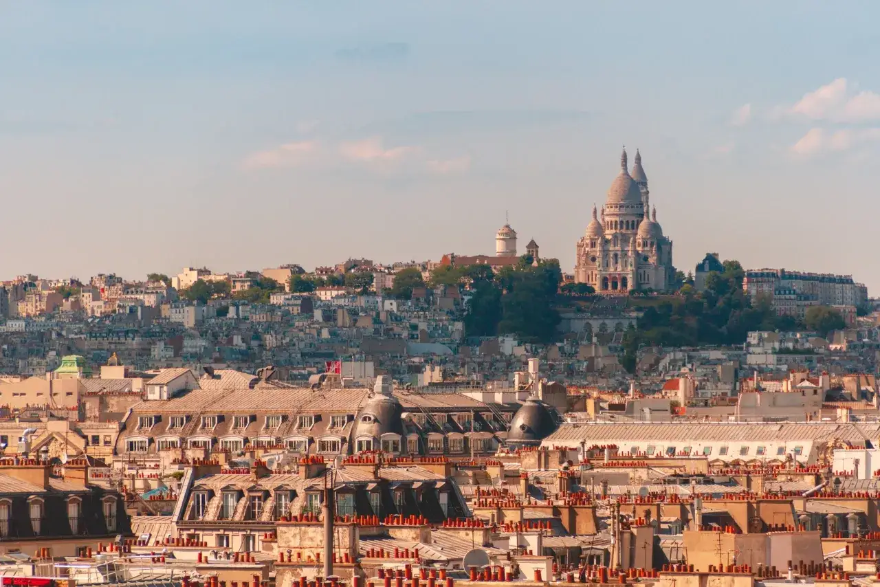 Widok na Paryż z bazyliką Sacré-Cœur na wzgórzu. Idealne miejsce, gdzie najlepiej nocować w Paryżu, to okolice Montmartre.