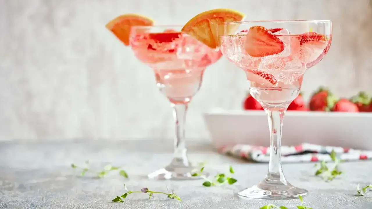 Dwa orzeźwiające drinki z truskawkami i plasterkami grejpfruta, przygotowane z czerwonego wina z wodą gazowaną.