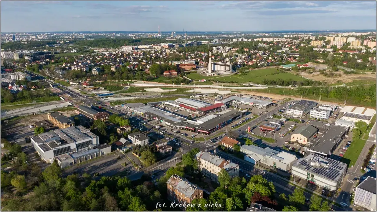 Widok z lotu ptaka na Kraków, z widocznym centrum sztuki współczesnej Solvay, otoczonym przez zabudowania i zieleń.