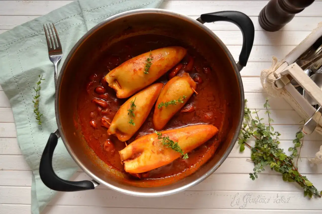 Calamari al sugo, ripieni e cotti in una ricca salsa di pomodoro, guarniti con timo fresco.