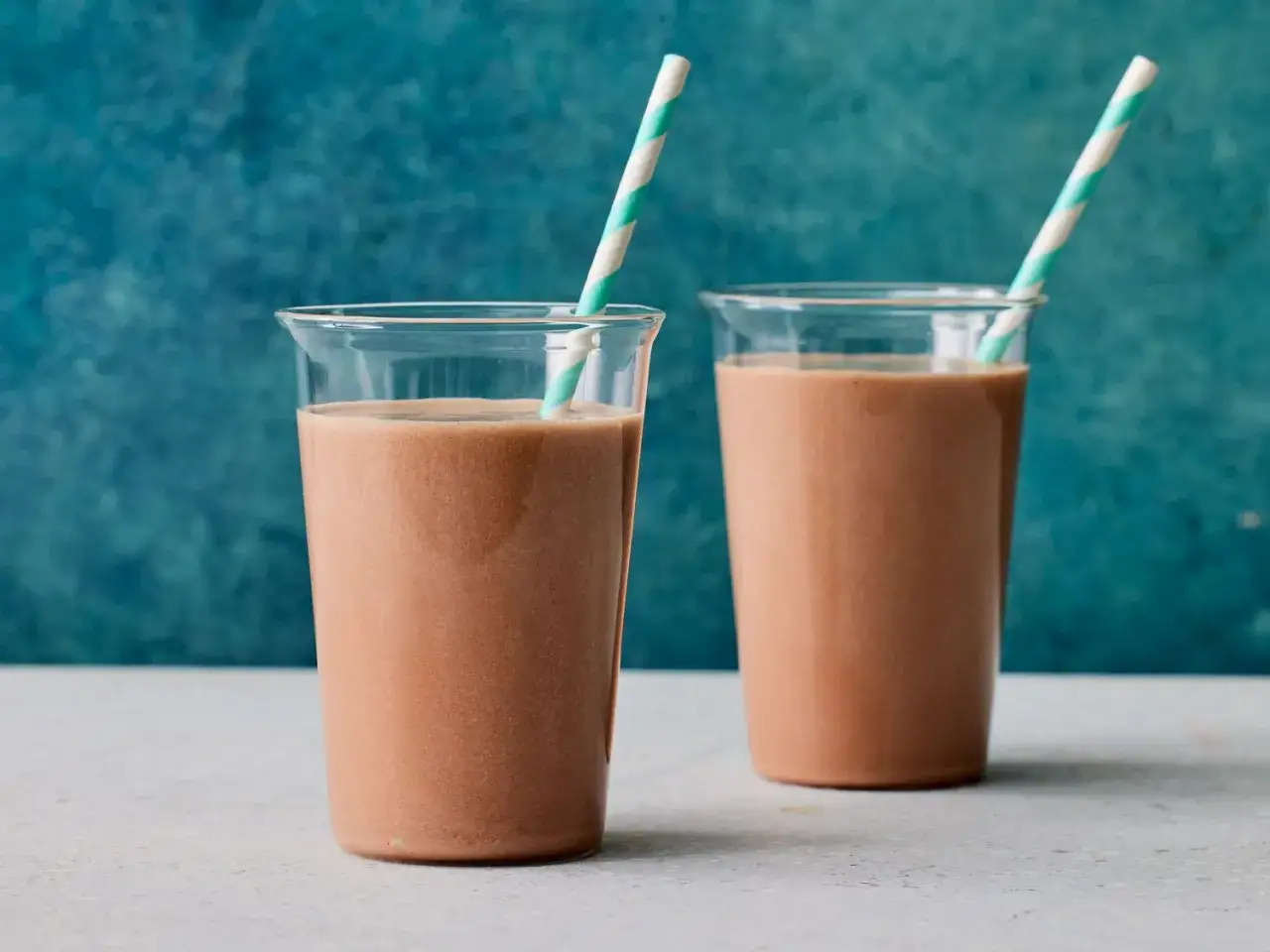 Zwei Gläser mit einem cremigen Schoko Protein Shake, bereit zum Genießen.