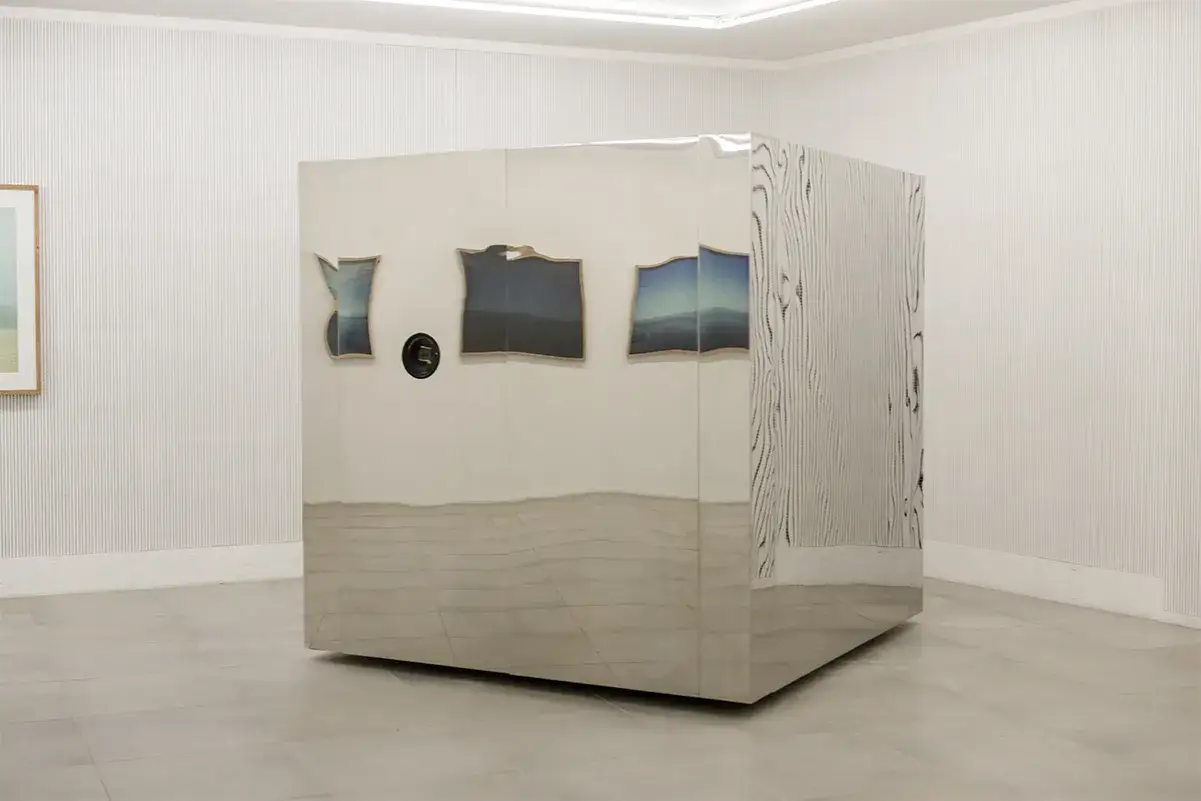 Installazione di Christian Martinelli: un cubo specchiato con immagini di paesaggi riflessi e un motivo a corteccia d'albero.