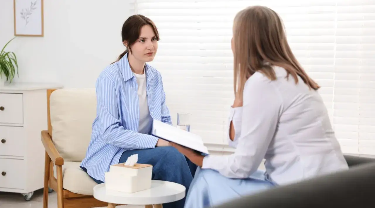 Młoda kobieta rozmawia z terapeutką. Kiedy iść do psychiatry? Gdy czujesz, że potrzebujesz wsparcia.