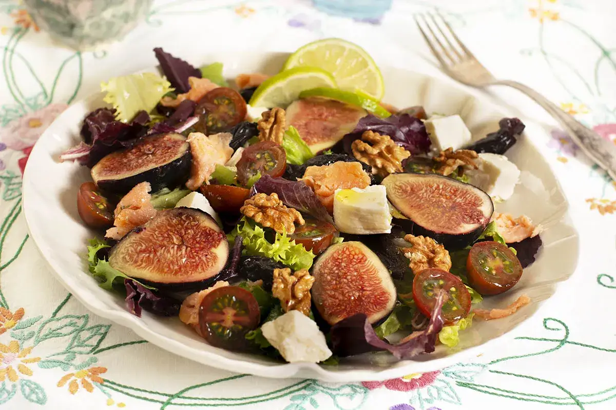 Ensalada con higos cortados, queso feta, nueces, tomates cherry y salm&oacute;n. Una delicia que muestra como se hacen los higos en una ensalada.
