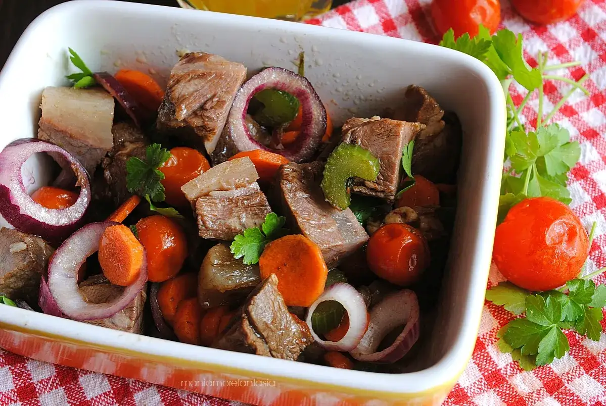 Un gustoso insalata di bollito con carne tenera, carote, cipolle rosse e pomodorini, guarnita con prezzemolo fresco.