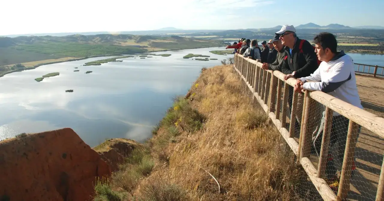 Grupo de personas observando un paisaje lacustre desde un mirador de madera. La **buruj&oacute;n ruta** ofrece vistas espectaculares.