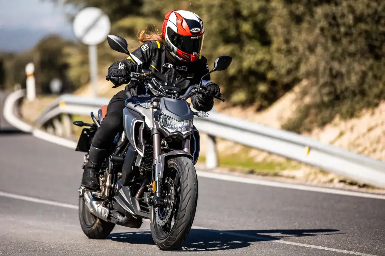 Motociclista en una Orcal SK 01 125, con casco HJC, disfrutando de un paseo por una carretera.