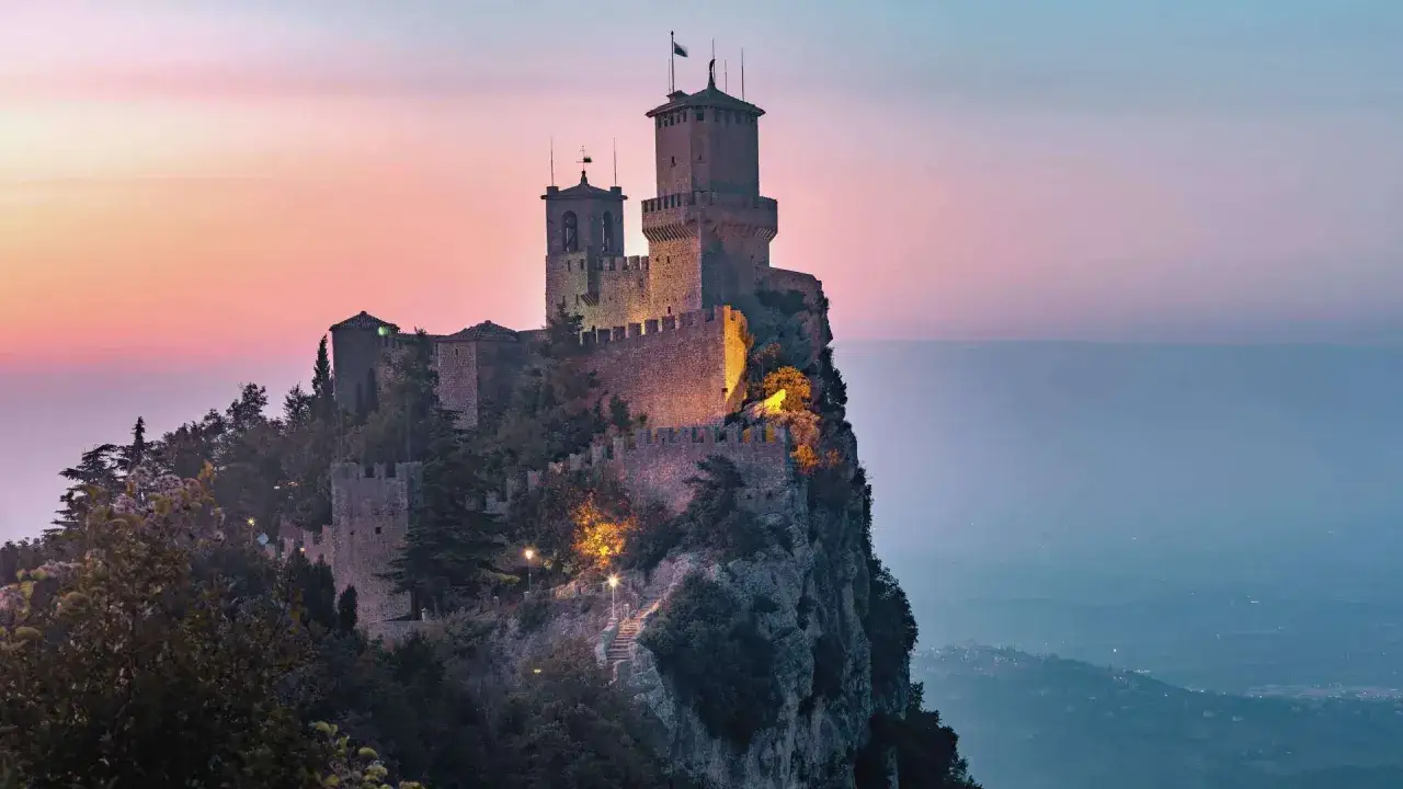 San Marino: en medeltida borg tronar p&aring; en klippa vid solnedg&aring;ngen, med en hisnande utsikt &ouml;ver landskapet.