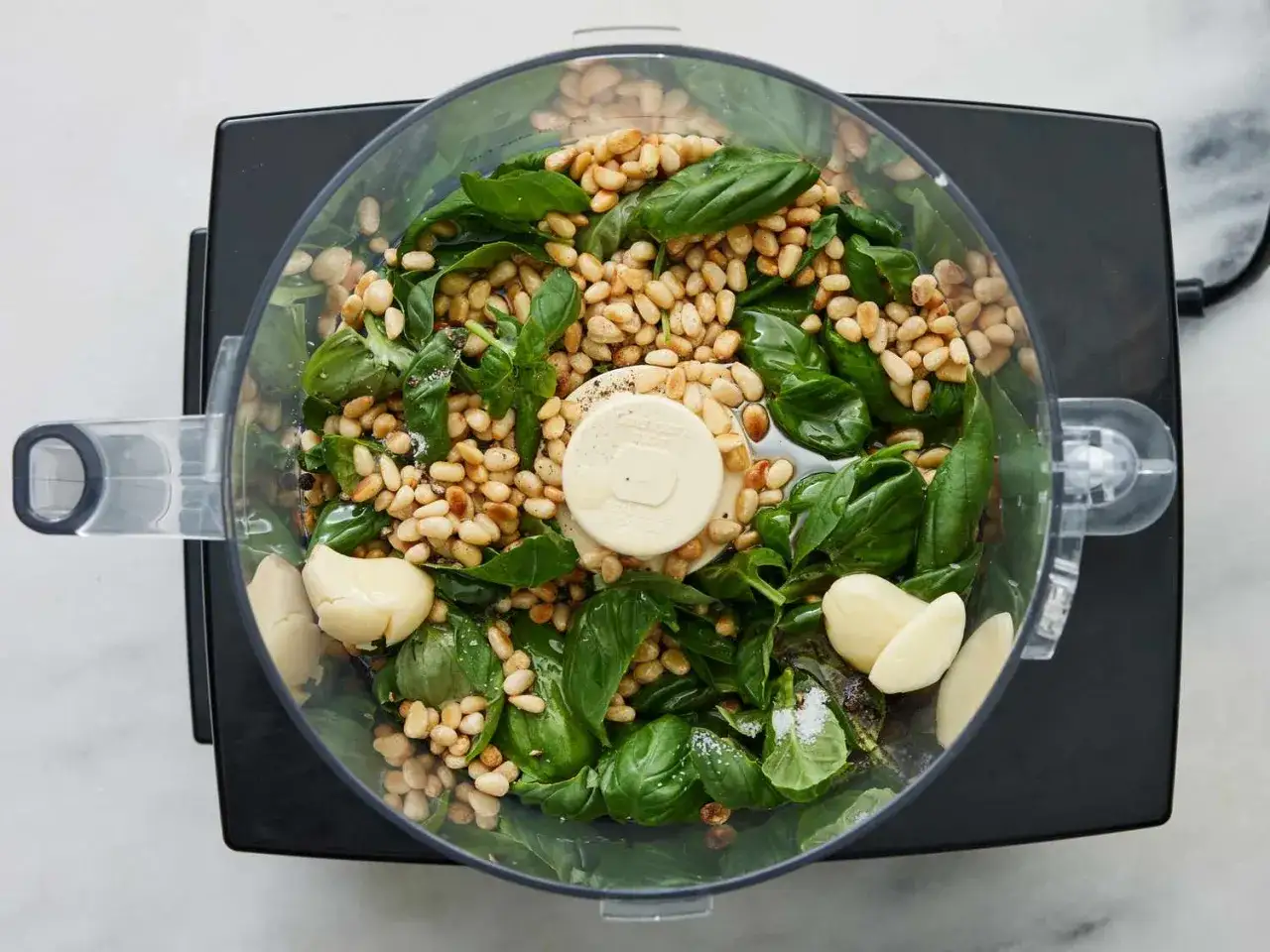 Składniki na pesto w malakserze: bazylia, orzeszki piniowe, czosnek. Czy pesto jest zdrowe? Tak, to pyszny i zdrowy dodatek!