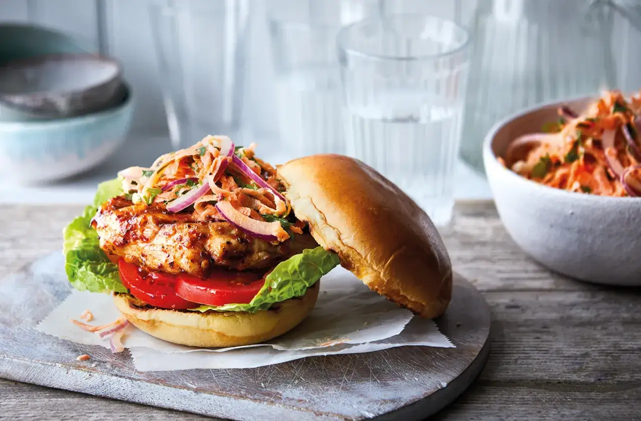 Pyszny burger z kurczakiem, soczysty pomidor, chrupiąca sałata i świeża surówka z marchewki i cebuli.
