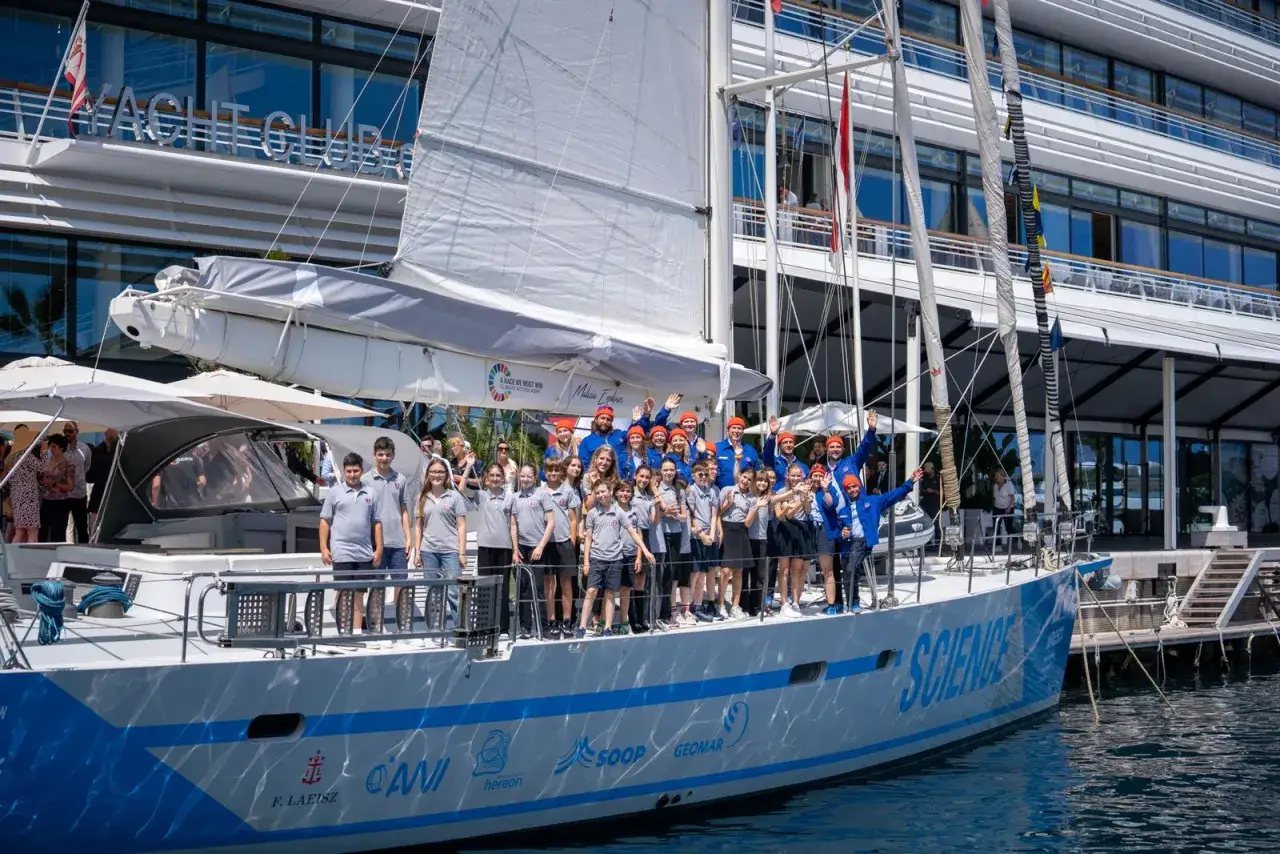 Eine Gruppe von Kindern und Erwachsenen steht auf einem Segelboot, das f&uuml;r die Malizia Ocean Race bereit ist.