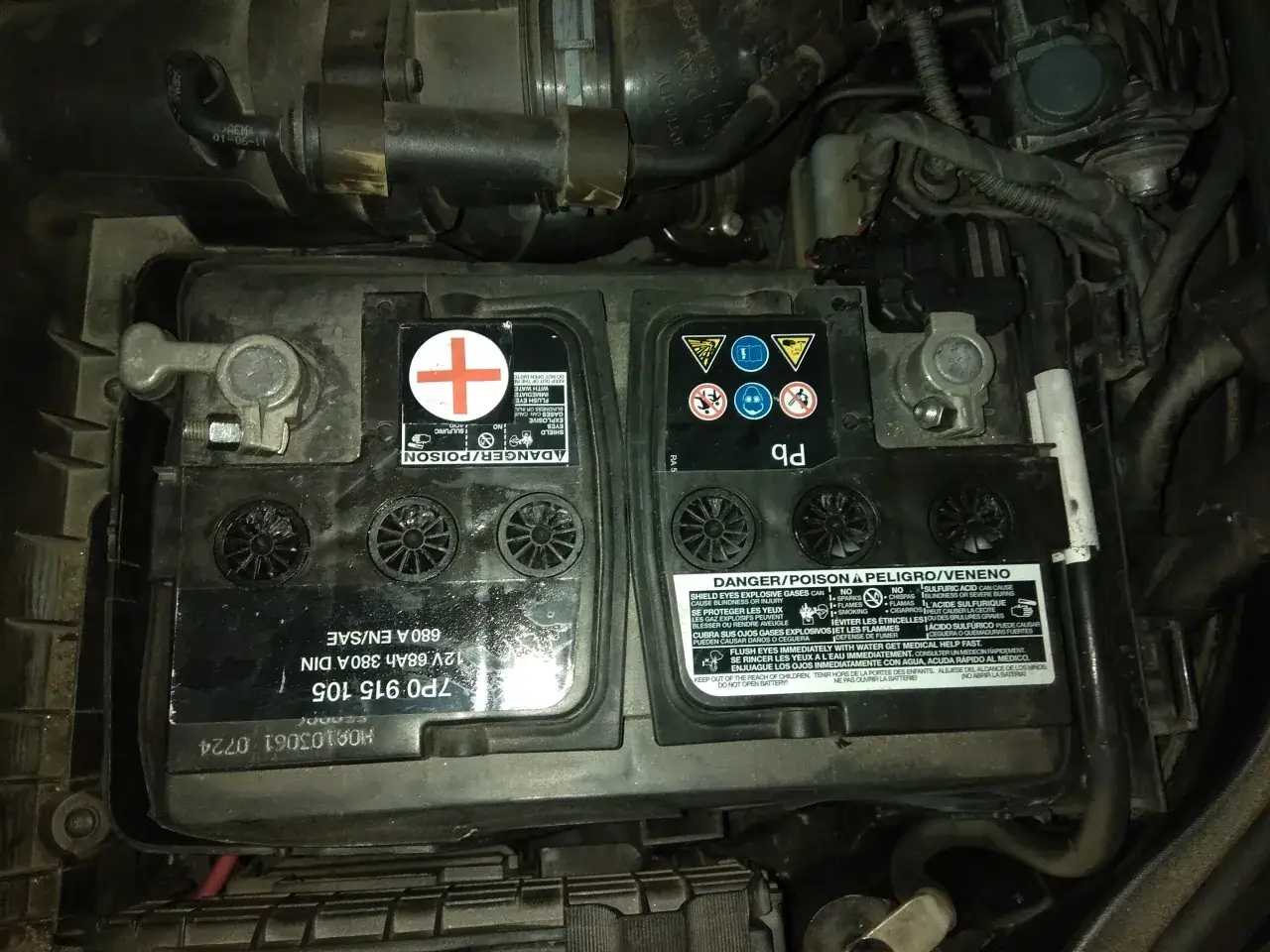 Akumulator Passat B7 2.0 TDI, widoczny w komorze silnika, z oznaczeniami producenta i ostrzeżeniami.