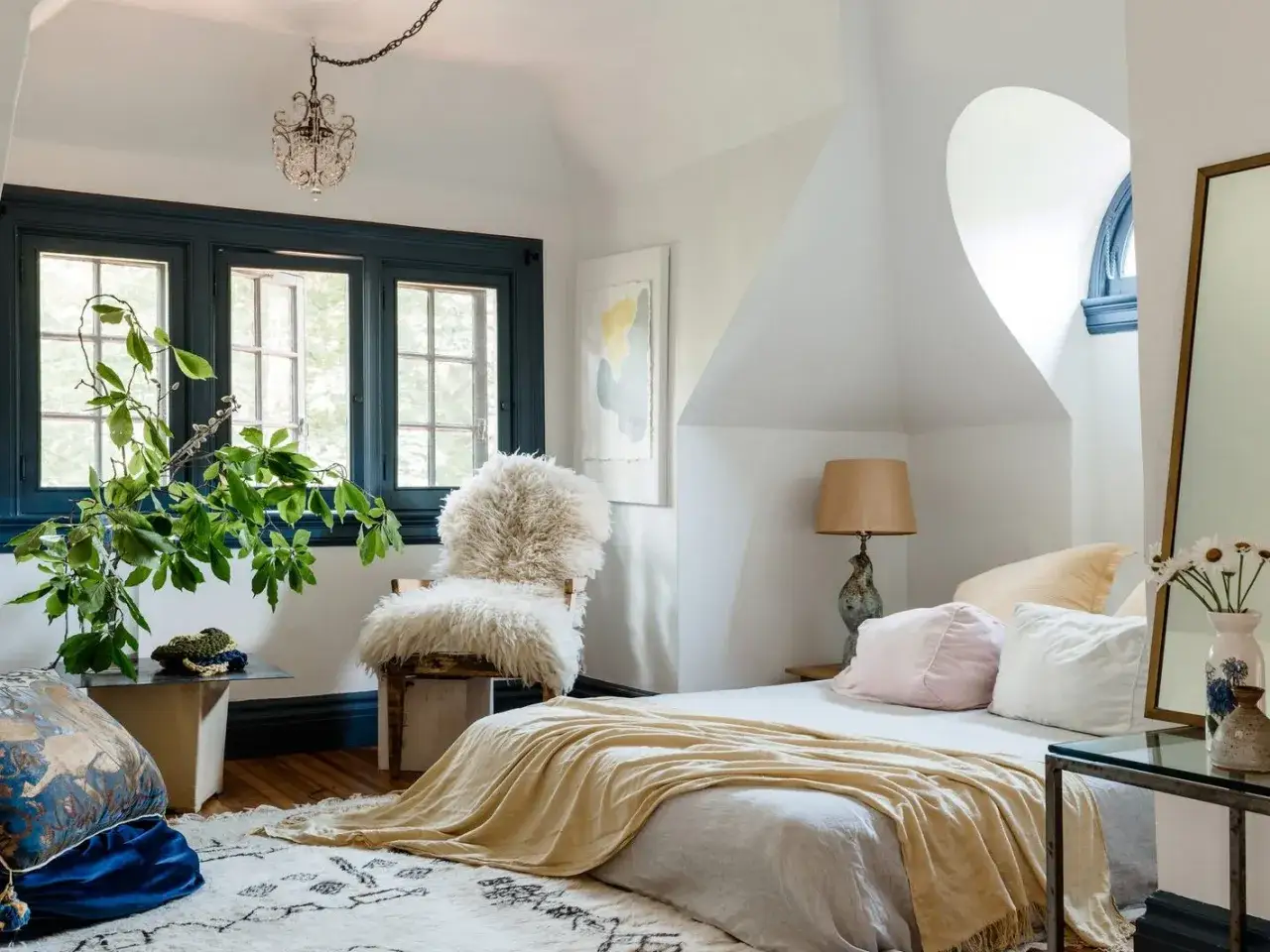 Gemütliches Schlafzimmer Design mit Lammfell-Stuhl, gelber Decke und grünen Pflanzen. Ein Traum zum Entspannen.