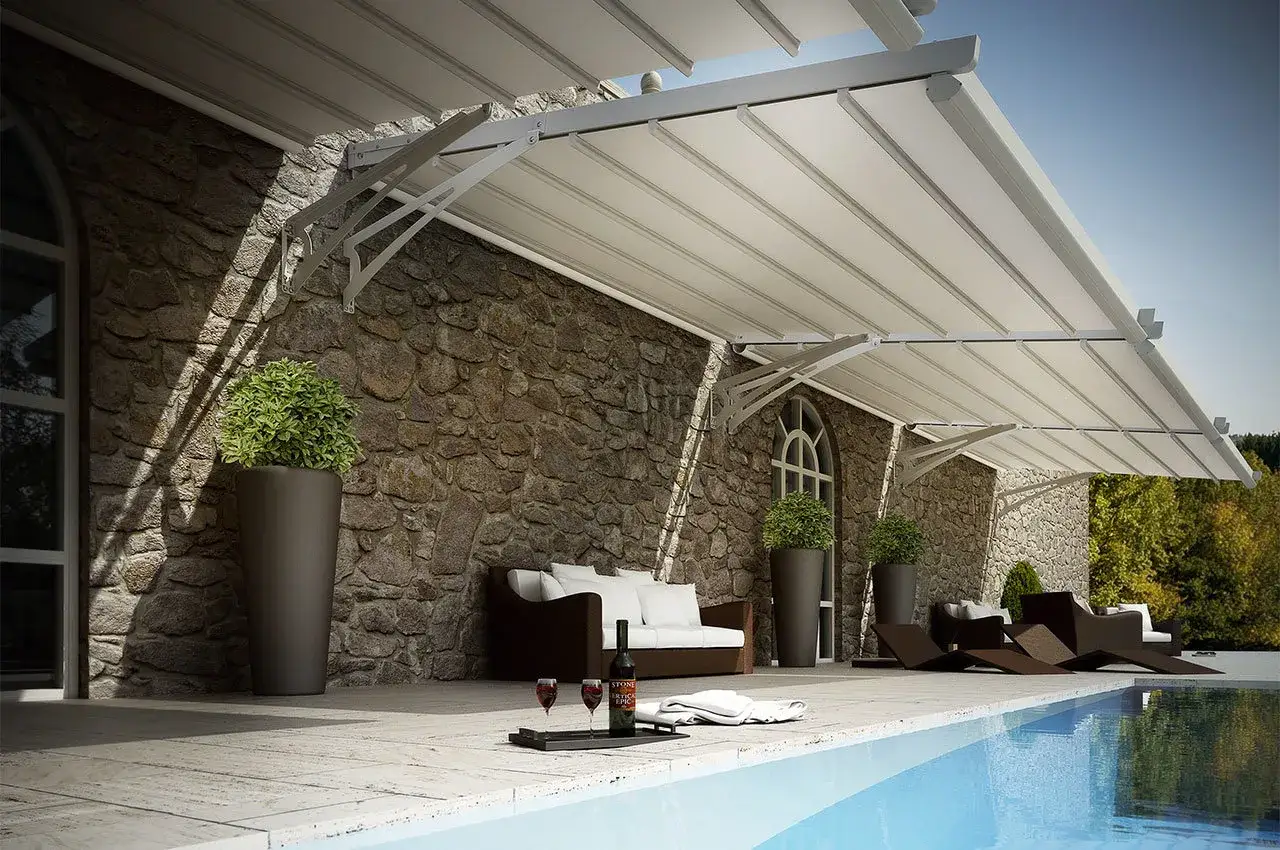 Pergola addossata in alluminio fai da te, con teli retrattili, arreda un patio con piscina, divano e sdraio.