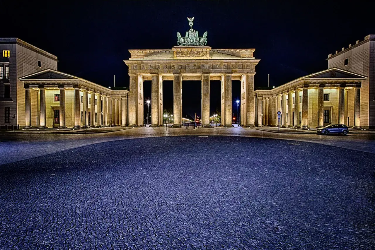 Das Brandenburger Tor bei Nacht, ein Muss, wenn man **cosa vedere a Berlino** sucht. Die Quadriga thront majestätisch über den Säulen.