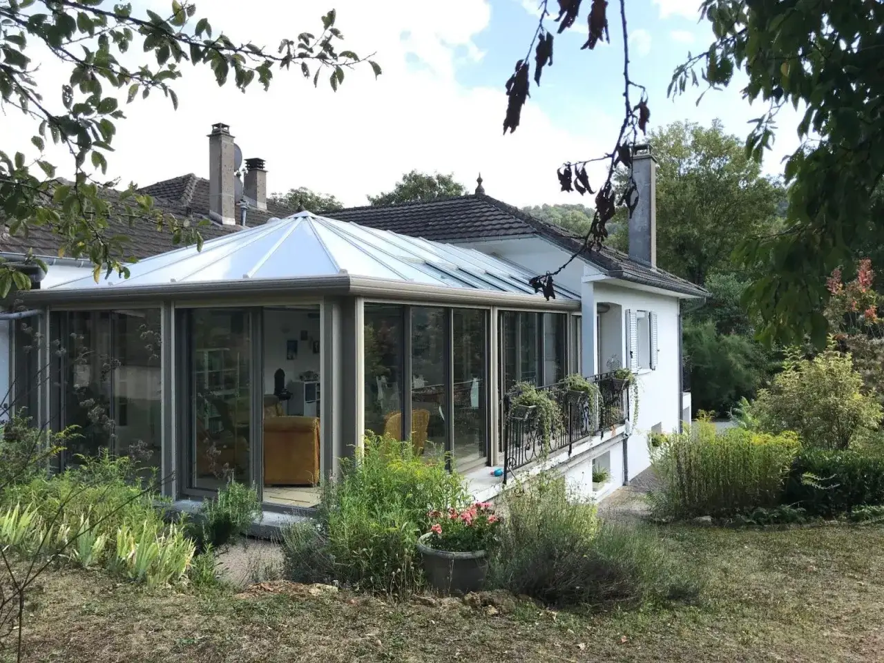 Une maison avec une **v&eacute;randa 2 pans** lumineuse, entour&eacute;e d'un jardin verdoyant.