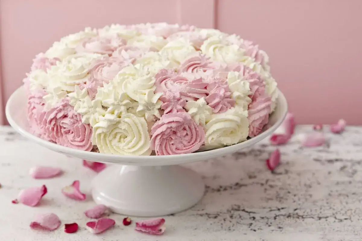En vacker tårta med fluffig cream cheese frosting i rosa och vitt, dekorerad som rosor. Perfekt för ett sommarfirande.