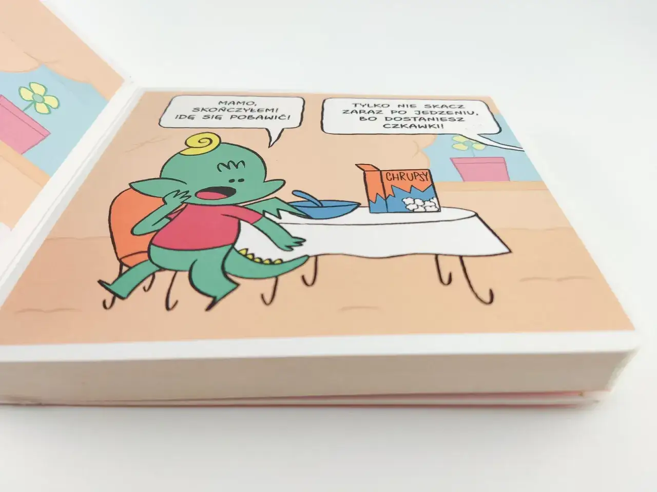 Zielony potworek kończy jeść chrupki i chce się bawić. Ilustracja z pierwszych komiks&oacute;w dla dzieci.
