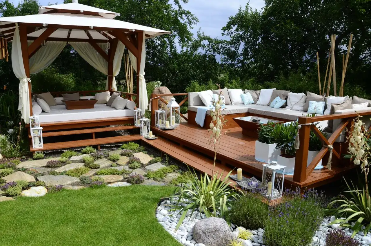 Un angolo relax con gazebo e divano ad L su una terrazza in legno. Idee giardino per un'oasi di pace.