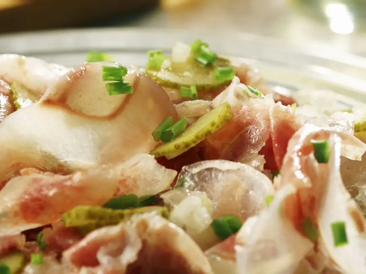 Nahaufnahme eines Ochsenmaulsalats mit Gurkenscheiben und Schnittlauch. Ein k&ouml;stliches Rezept f&uuml;r den Sommer.