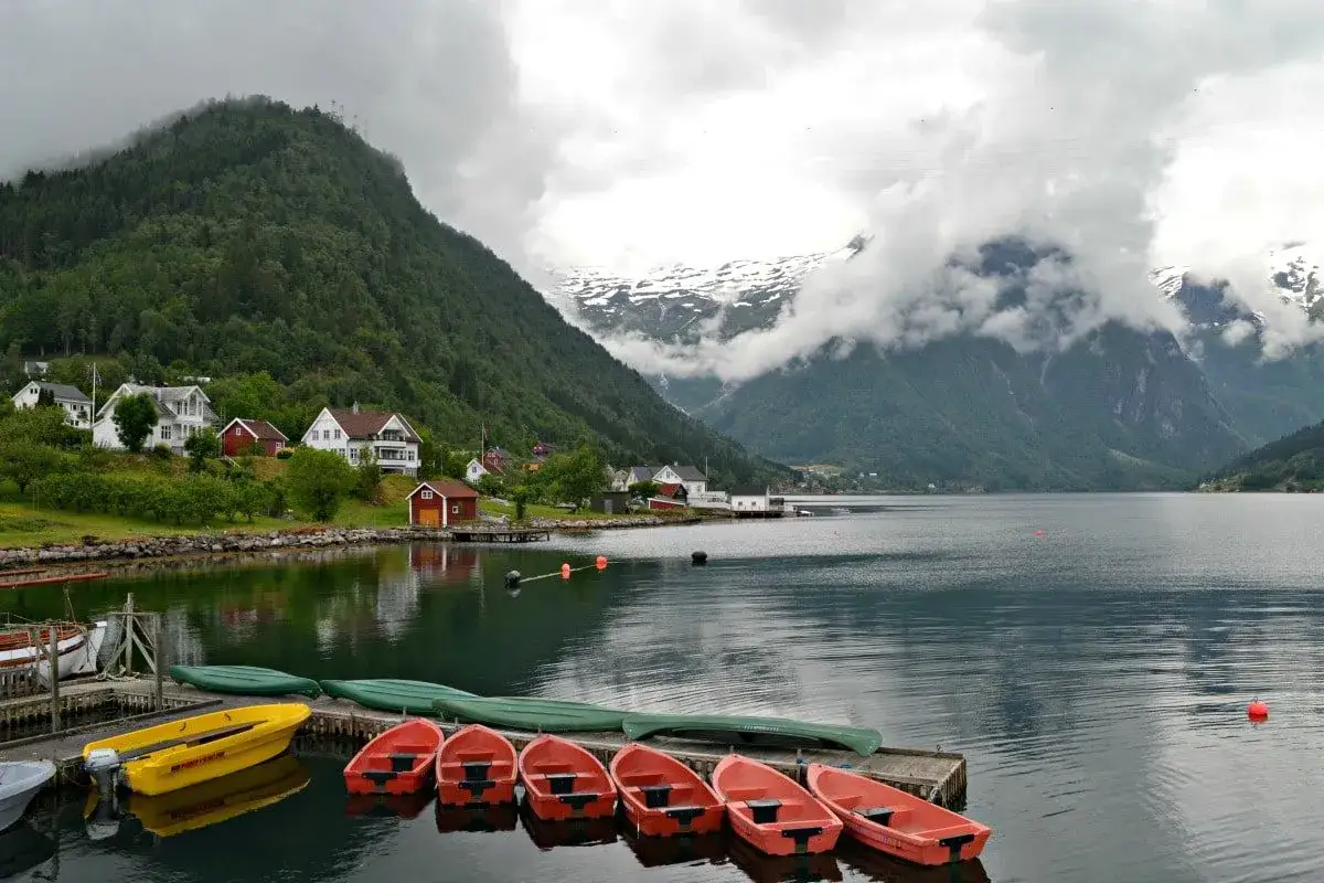 Norwegia z dziećmi: malowniczy fiord, domki na zboczu, ł&oacute;dki na wodzie. Idealne miejsce na rodzinne wakacje.