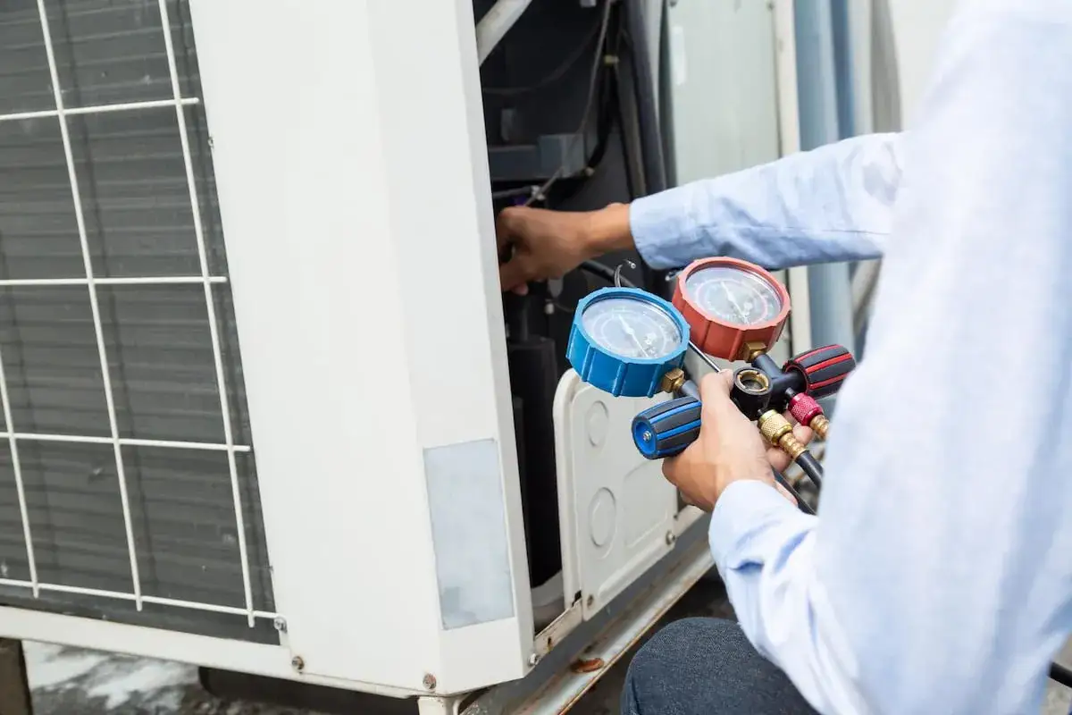 Technicien v&eacute;rifiant la pression d'un climatiseur avec des manom&egrave;tres. Un bon entretien est essentiel pour le prix de l'entretien climatisation.