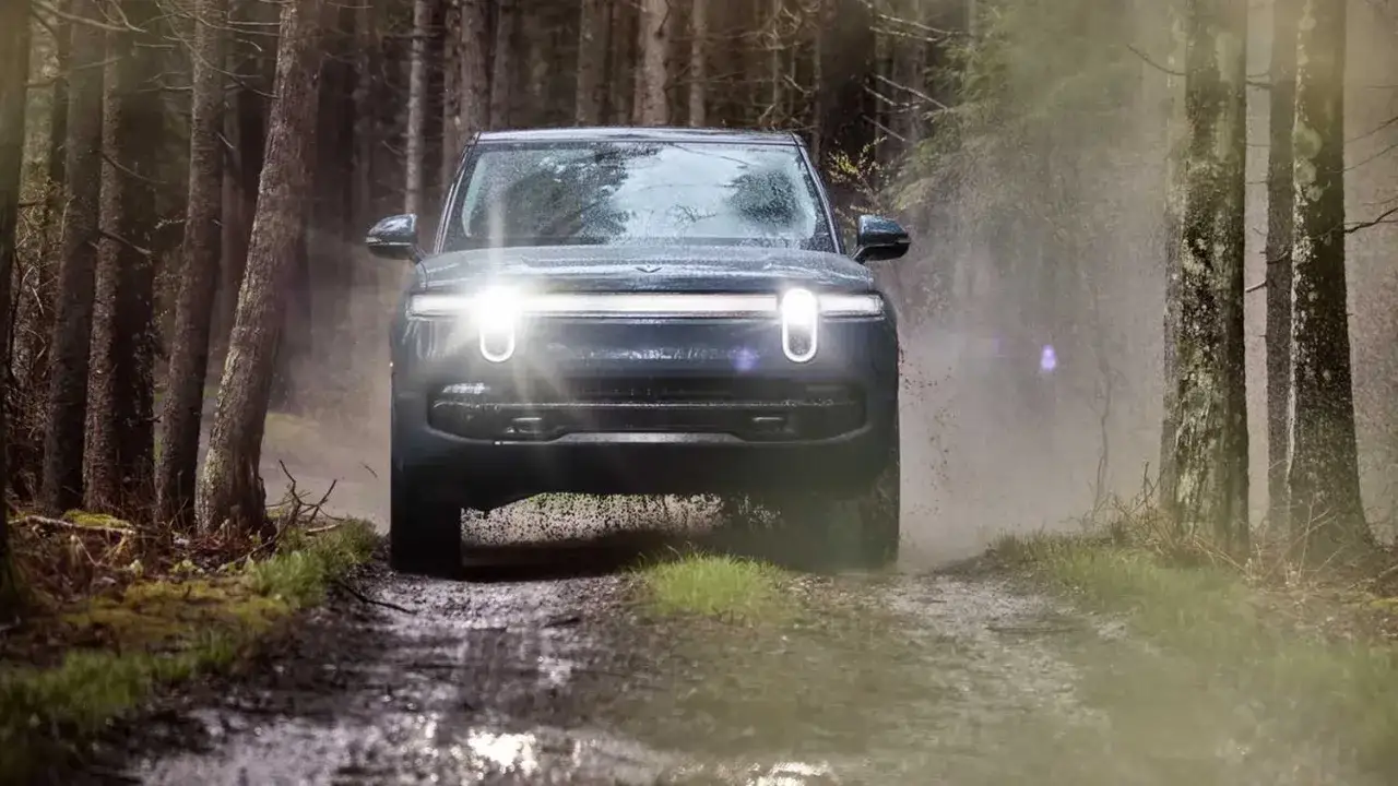 Ciemny, luksusowy SUV premium pokonuje błotnistą leśną ścieżkę, rozpryskując wodę.