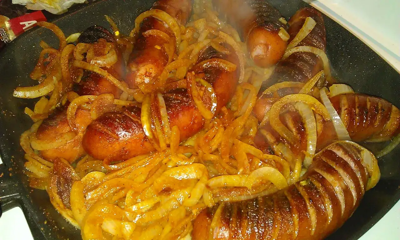Smażona kiełbasa śląska z cebulką na patelni. Idealny sposób, by dowiedzieć się, ile gotować kiełbasę śląską, by była pyszna.