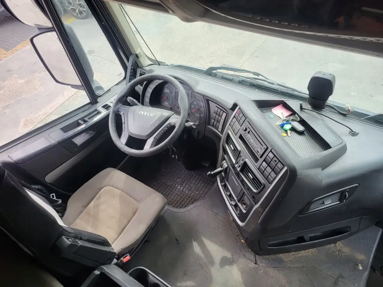 Wnętrze Iveco Stralis: kierownica, deska rozdzielcza z radiem i przyciskami, fotel kierowcy i dźwignia zmiany biegów.