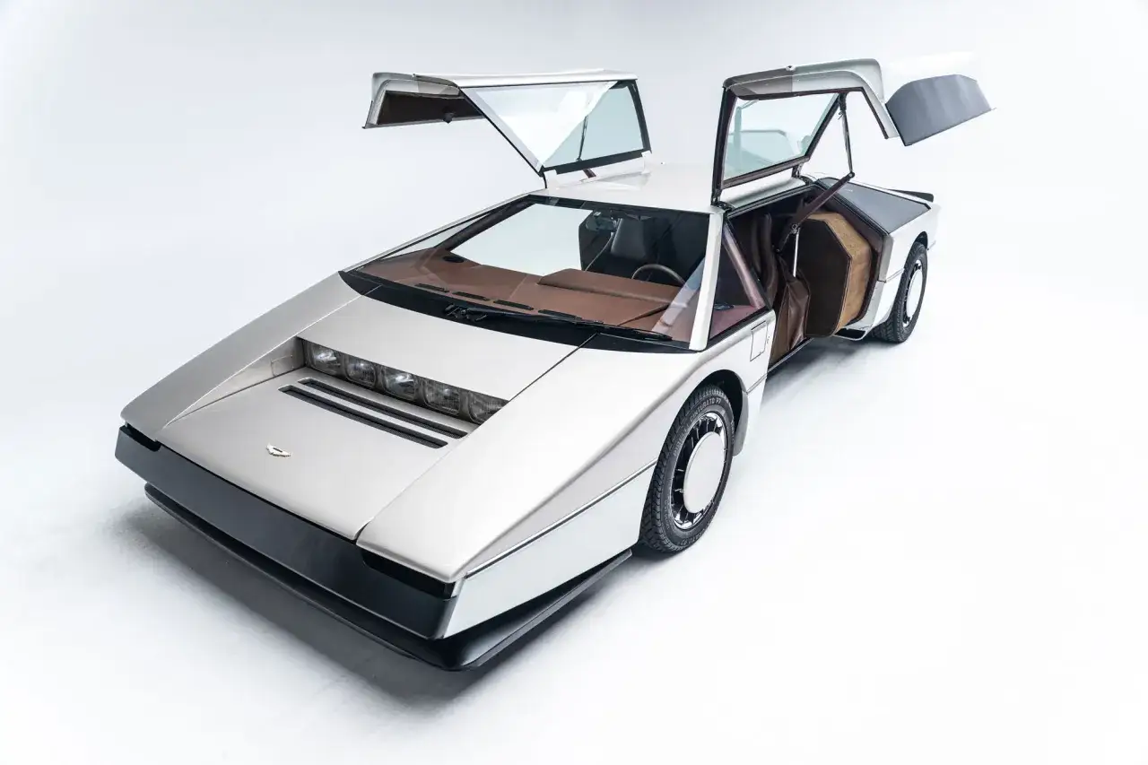 Srebrny Lotus Esprit z lat 80. z otwartymi drzwiami typu gullwing, wnętrze w brązie.