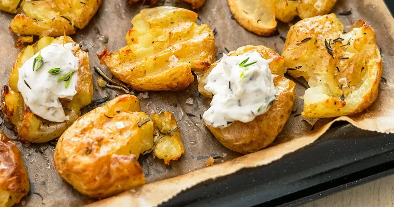 Knusprig gebackene smashed potatoes mit Kr&auml;uterquark und Rosmarin, bereit zum Genie&szlig;en.