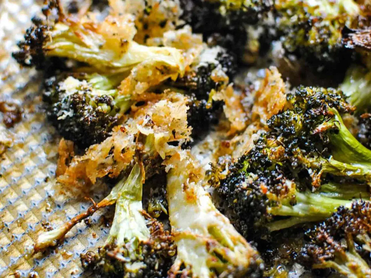 Knusprig gebratener Brokkoli mit Parmesan auf einem Backblech.