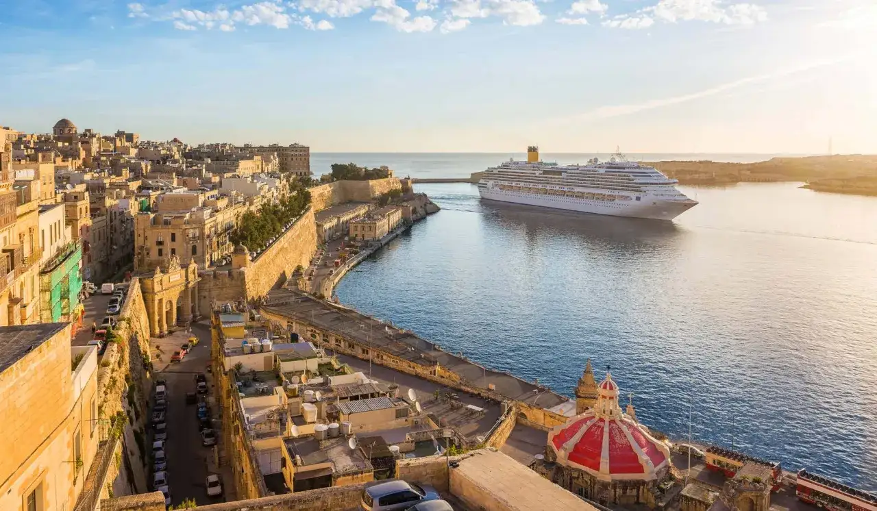 Una nave da crociera solca le acque di un porto storico, promettendo una crociera corta indimenticabile tra antiche mura e il mare azzurro.