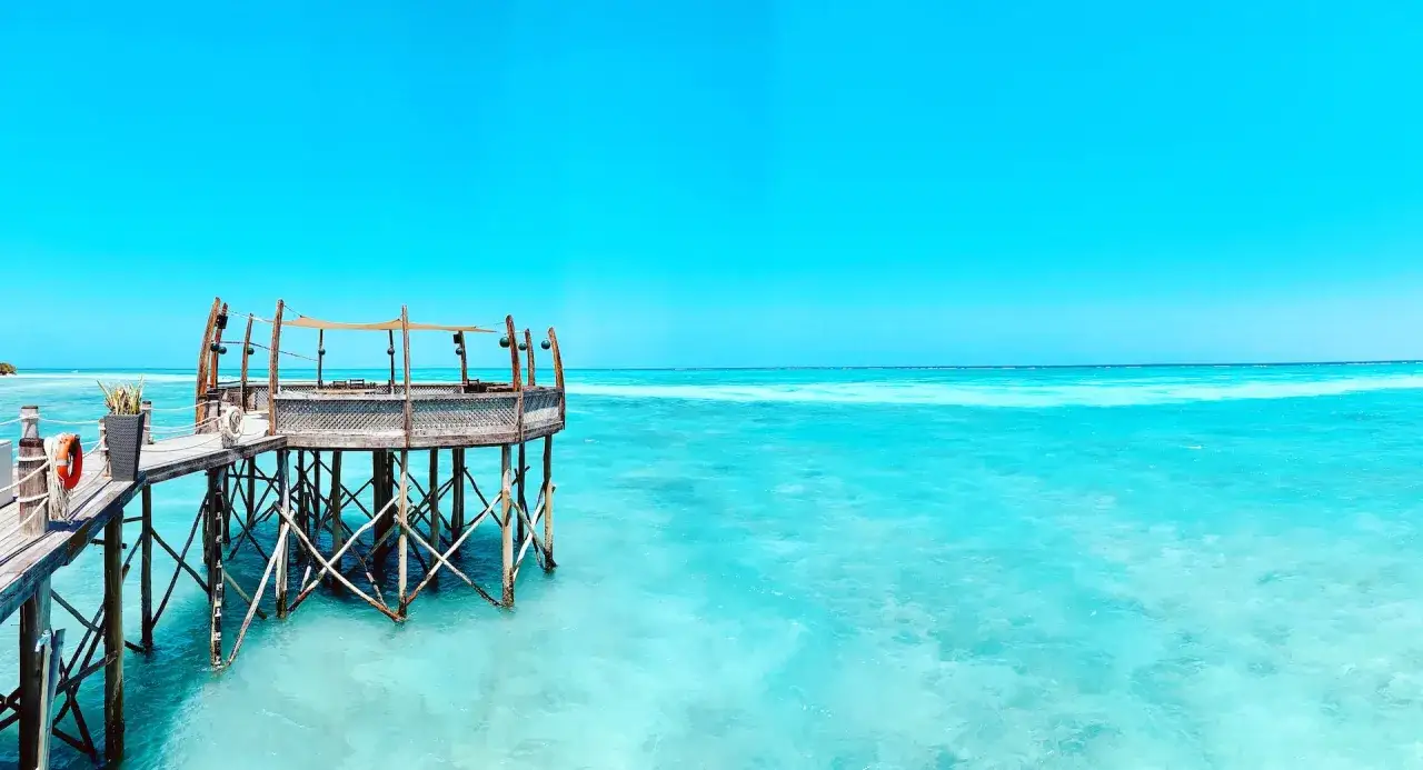 Drewniany pomost prowadzi do restauracji na wodzie. Idealne miejsce na relaks po dniu pełnym wrażeń, jak safari z Zanzibaru.