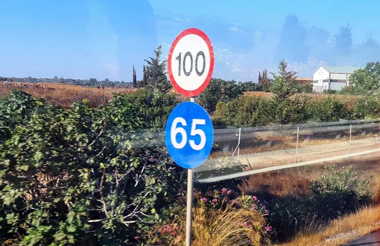 Znaki drogowe: 100 km/h i 65 km/h. Ten drugi oznacza minimalna prędkość na autostradzie, gdy droga jest pusta.