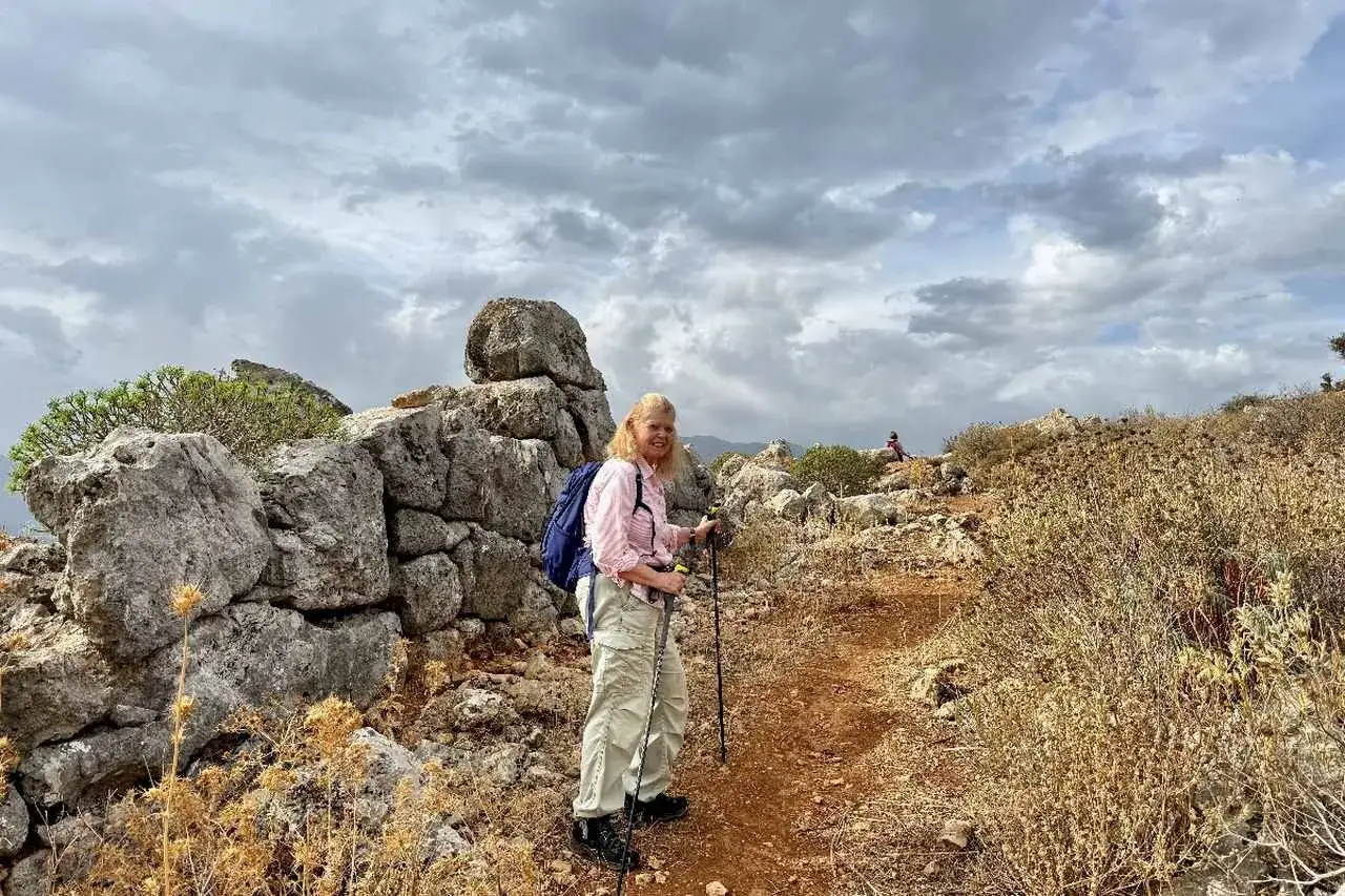 Une femme randonne sur un sentier rocailleux en Crète, profitant du paysage. Une excellente idée de que faire en Crète pour les amateurs de nature.