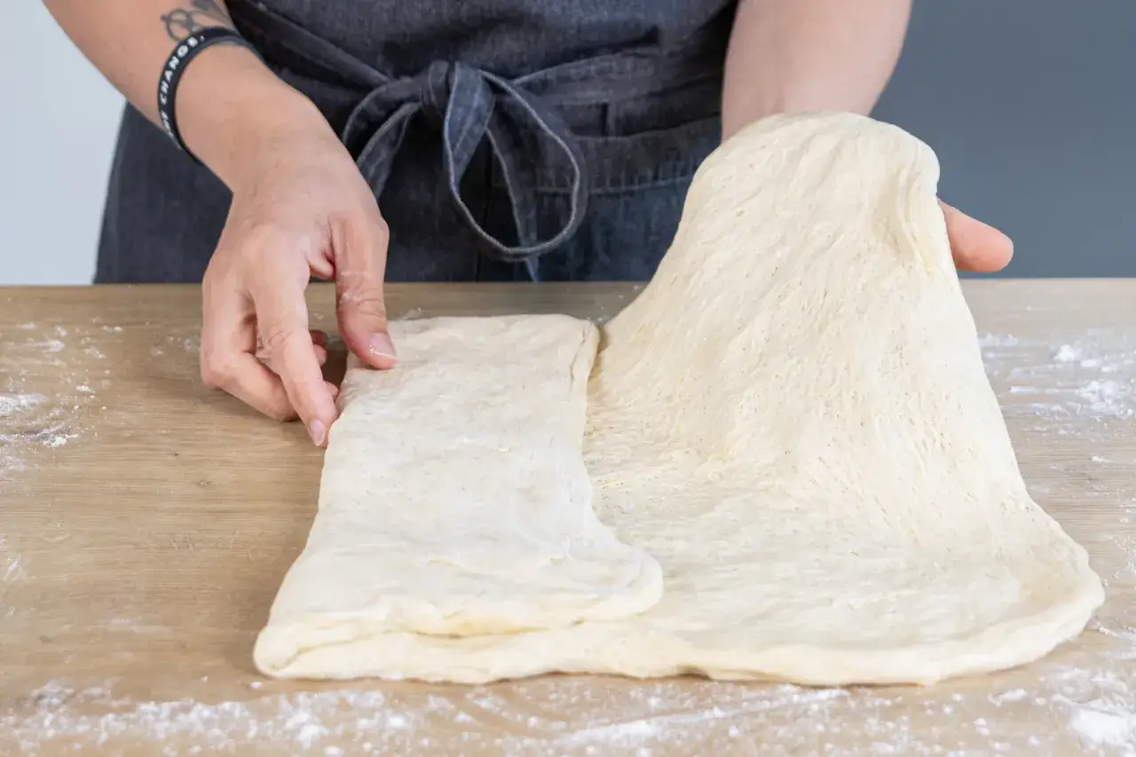 Hände falten Teig für Ciabatta. So gelingt Ciabatta selber backen leicht.