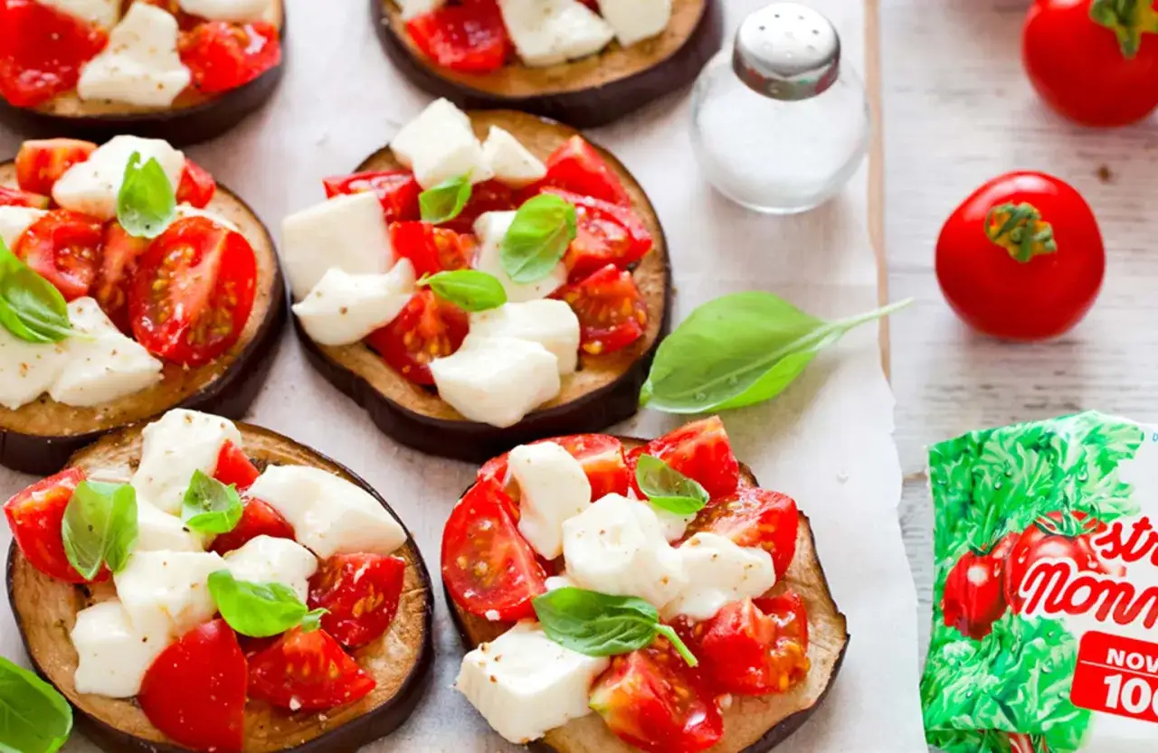 Pizzette di melanzane con pomodorini freschi, mozzarella e basilico. Un antipasto leggero e gustoso.