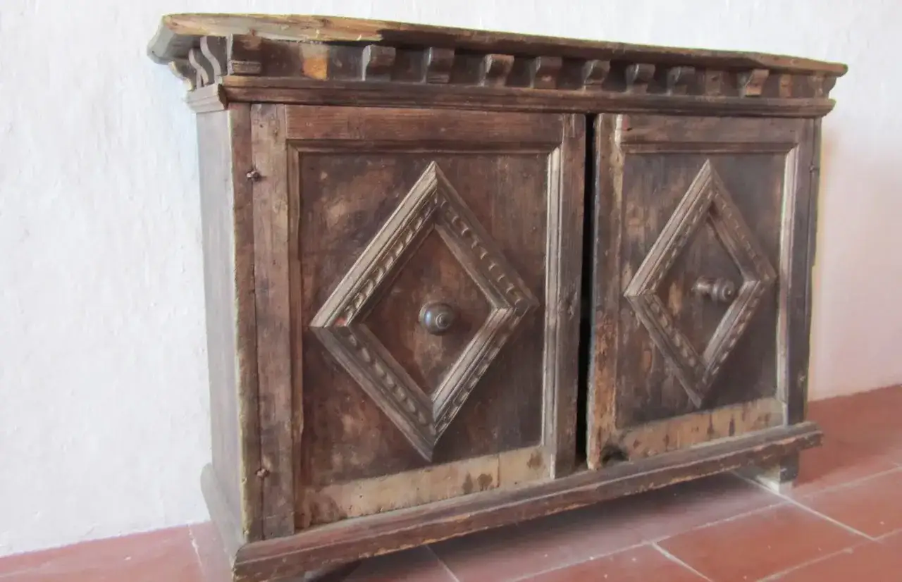 Mobiletto in legno scuro con due ante a rombo, ideale per riportare il legno al naturale e valorizzare il suo aspetto vissuto.