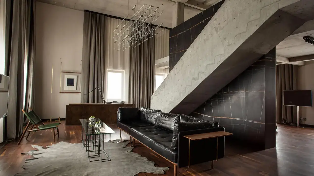 Nowoczesny apartament z czarną skórzaną kanapą i betonowymi schodami, idealny dla sieci luksusowych hoteli.