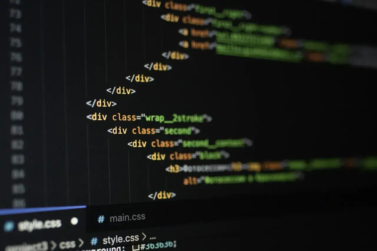 Kod HTML i CSS na ciemnym tle. Dowiedz się, jak otworzyć plik HTML w przeglądarce, aby zobaczyć efekt swojej pracy.