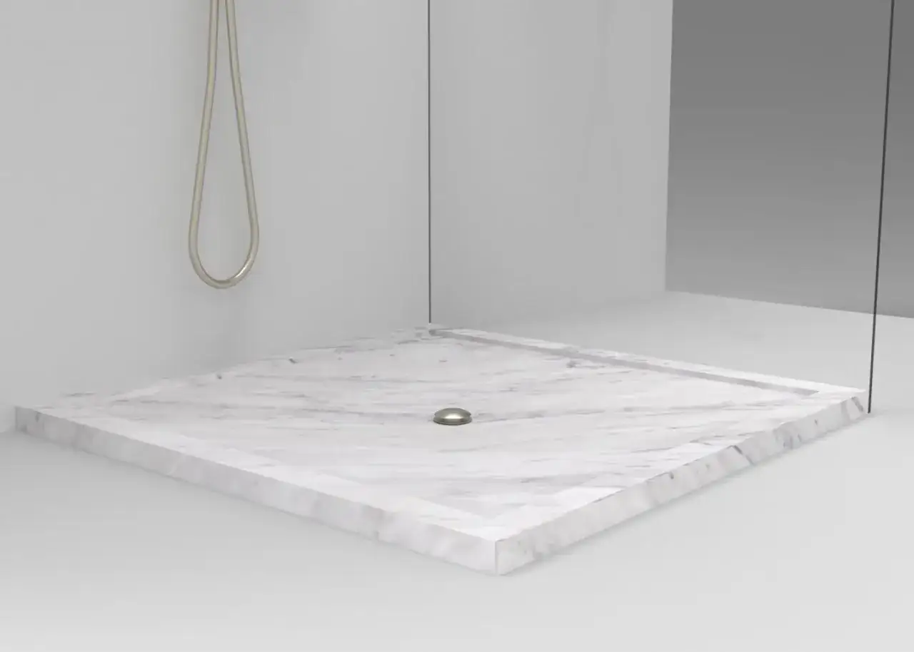 Piatto doccia in marmo bianco con montaggio a filo pavimento, scarico centrale e soffione doccia cromato.