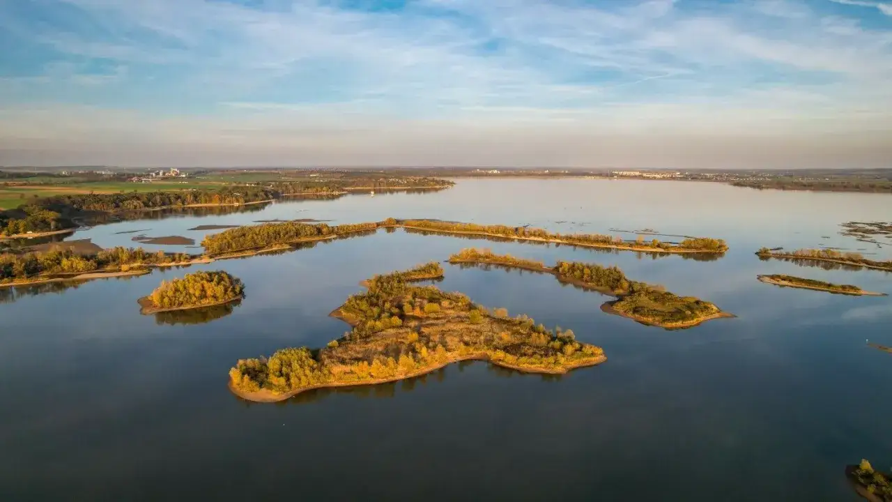 Malownicze wyspy porośnięte jesiennymi drzewami na spokojnej wodzie. Krajobraz przypomina najmniejsze województwo w Polsce, pełne urokliwych zakątków.