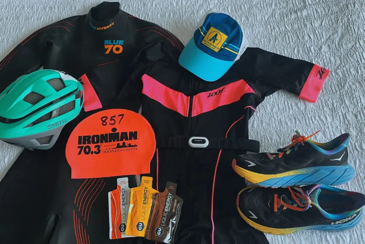 Ausr&uuml;stung f&uuml;r einen Triathlon Kurzdistanz: Neoprenanzug, Helm, Badekappe, Laufanzug, Gels, Laufschuhe und eine Kappe.