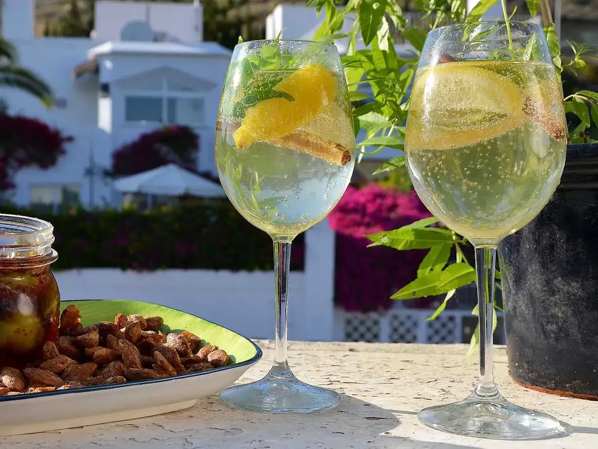 Två glas med bubblig vit sangria, garnerade med citron och kanel. Perfekt för ett somrigt vit sangria recept.